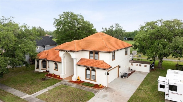 mediterranean / spanish home with a front lawn, stucco siding, a tiled roof, an attached garage, and driveway