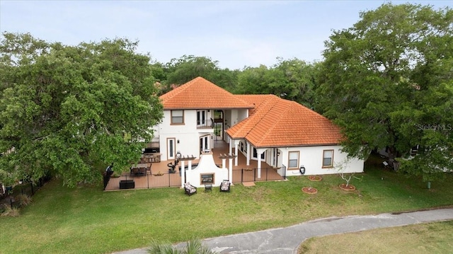 back of house featuring a tiled roof, a patio area, a balcony, a yard, and stucco siding