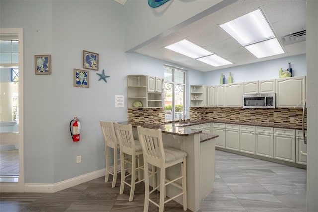5300 S Atlantic Ave Unit 8-304, New Smyrna Beach, FL 32169 - kitchen featuring open shelves, a breakfast bar, stainless steel microwave, a peninsula, and tasteful backsplash