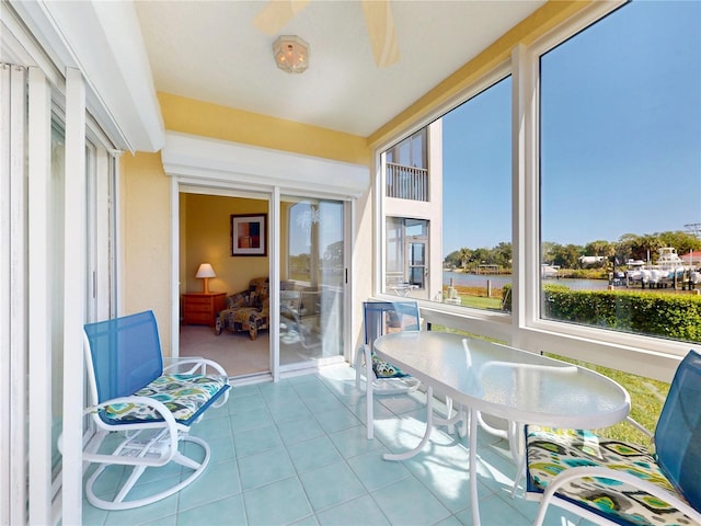 sunroom / solarium with a water view and tile patterned floors