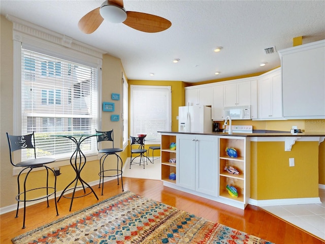 kitchen with open shelves, visible vents, a ceiling fan, white appliances, and light wood-style floors