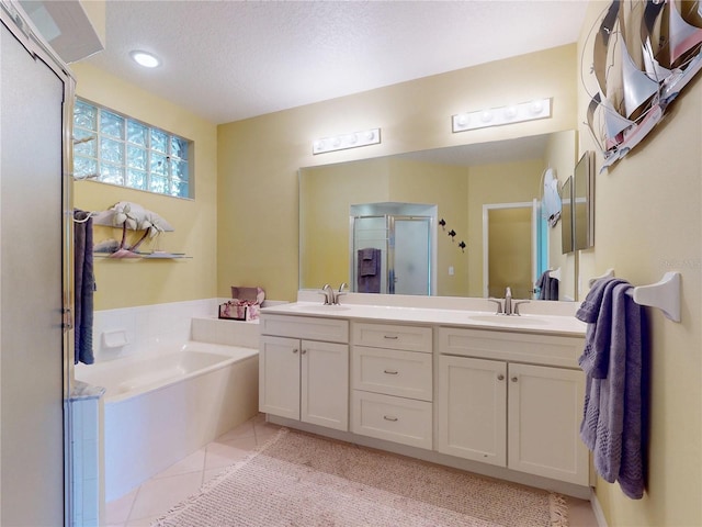 bathroom featuring tile patterned flooring, a garden tub, a sink, and a stall shower