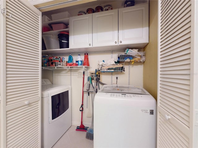 laundry area with washing machine and clothes dryer, cabinet space, and tile patterned flooring
