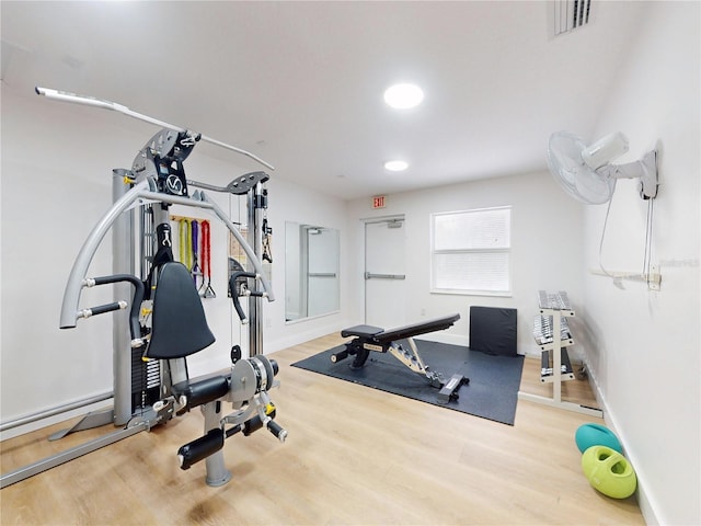 exercise room featuring baseboards, wood finished floors, and visible vents