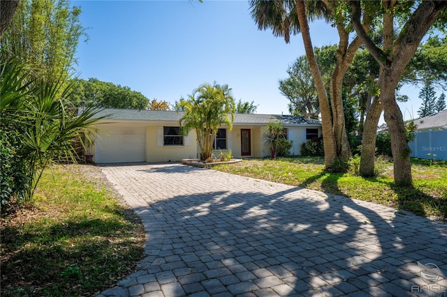 ranch-style home with an attached garage, fence, and decorative driveway
