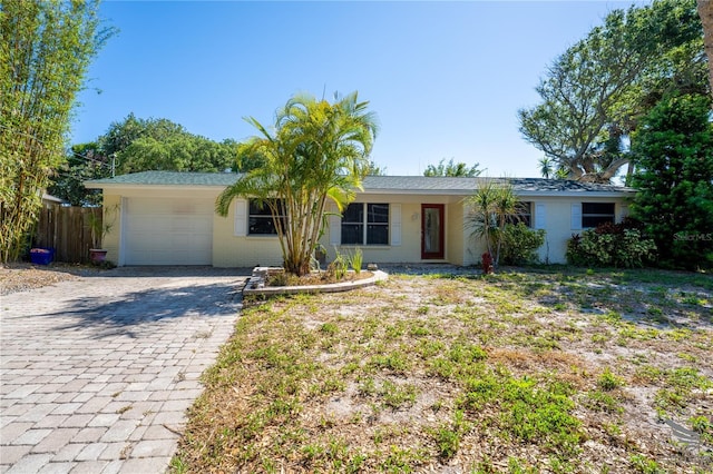 ranch-style house with fence, decorative driveway, and a garage