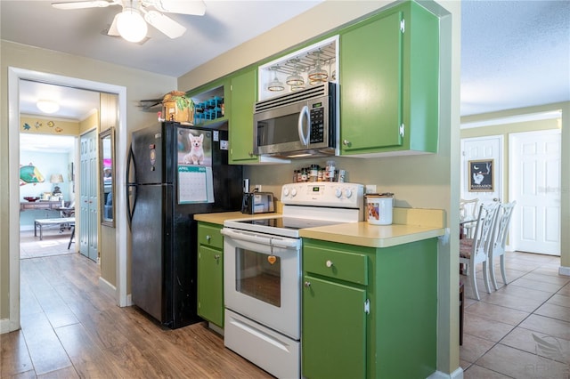 kitchen with light countertops, stainless steel microwave, freestanding refrigerator, green cabinets, and electric range