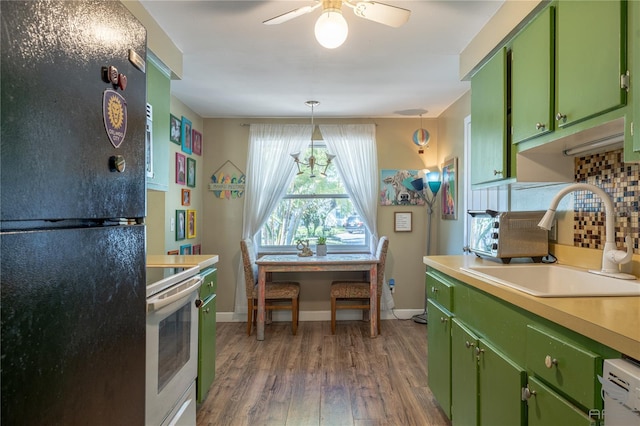 kitchen featuring white electric range, a sink, freestanding refrigerator, green cabinets, and tasteful backsplash