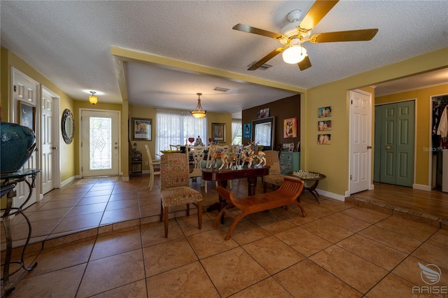 dining area featuring a textured ceiling, light tile patterned flooring, visible vents, baseboards, and ceiling fan