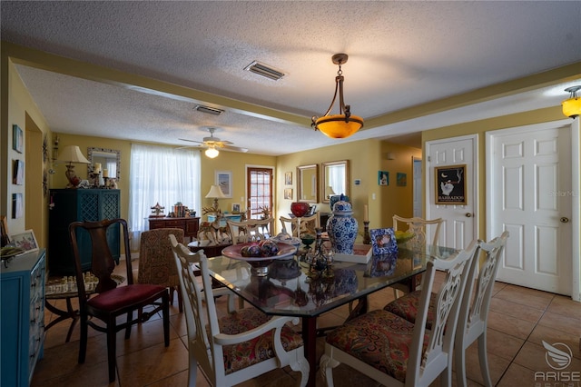 dining area with a ceiling fan, tile patterned floors, visible vents, and a textured ceiling