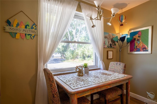 dining space featuring wood finished floors, baseboards, a notable chandelier, and a healthy amount of sunlight