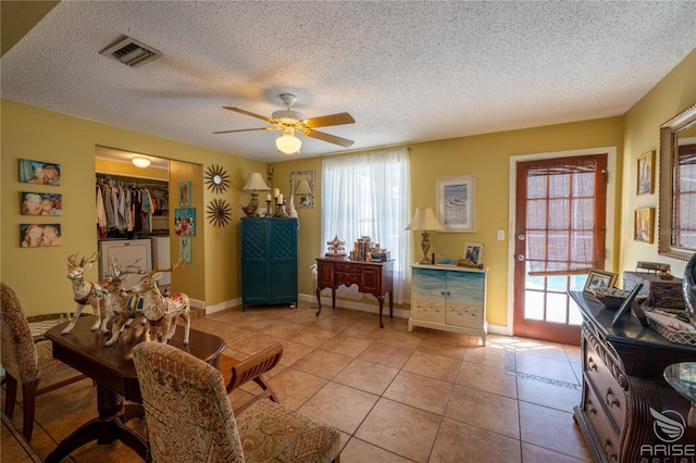 sitting room with a wealth of natural light, visible vents, independent washer and dryer, and ceiling fan