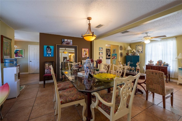 dining room featuring visible vents, a ceiling fan, light tile patterned floors, baseboards, and a textured ceiling