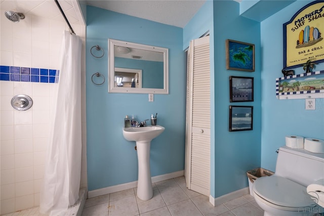 full bathroom featuring a tile shower, toilet, baseboards, and tile patterned floors