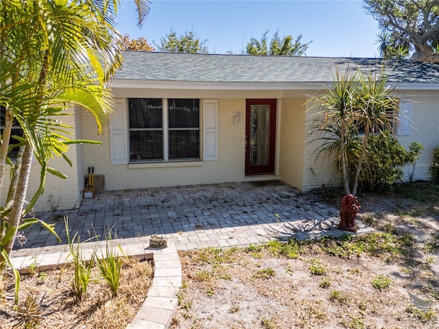 view of front of house featuring brick siding and roof with shingles