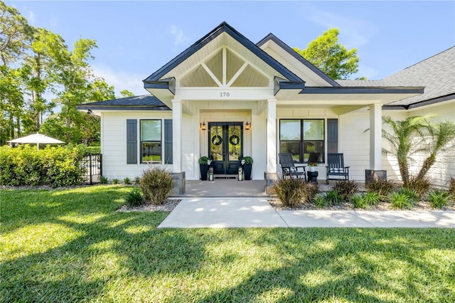 170 Live Oak Ct, New Smyrna Beach, FL 32168 - view of front of house with french doors, a front lawn, and covered porch