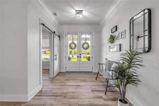 170 Live Oak Ct, New Smyrna Beach, FL 32168 - entrance foyer with light wood-type flooring, a textured ceiling, ornamental molding, a barn door, and french doors