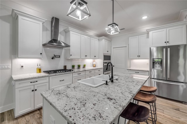 170 Live Oak Ct, New Smyrna Beach, FL 32168 - kitchen with white cabinets, a sink, wall chimney range hood, appliances with stainless steel finishes, and light wood-style floors