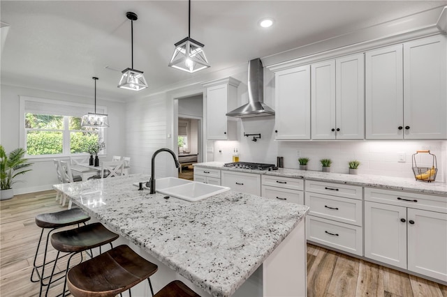 170 Live Oak Ct, New Smyrna Beach, FL 32168 - kitchen with tasteful backsplash, wall chimney range hood, white cabinetry, light wood finished floors, and a sink