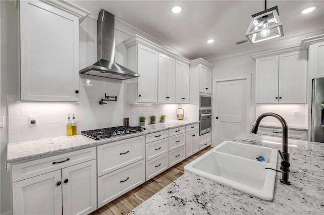 170 Live Oak Ct, New Smyrna Beach, FL 32168 - kitchen featuring tasteful backsplash, white cabinets, a sink, wall chimney range hood, and appliances with stainless steel finishes