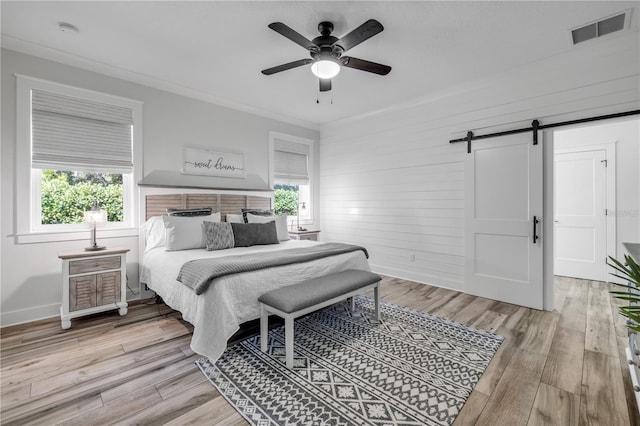 170 Live Oak Ct, New Smyrna Beach, FL 32168 - bedroom with a barn door, visible vents, multiple windows, and light wood-style flooring