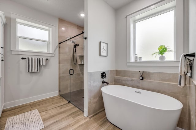 170 Live Oak Ct, New Smyrna Beach, FL 32168 - bathroom with a stall shower, wood finished floors, a soaking tub, and tile walls
