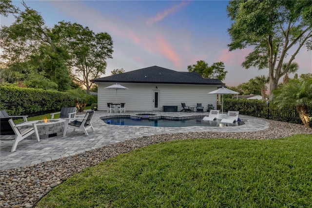 170 Live Oak Ct, New Smyrna Beach, FL 32168 - back of property at dusk featuring a patio, an in ground hot tub, an outdoor fire pit, fence, and a lawn