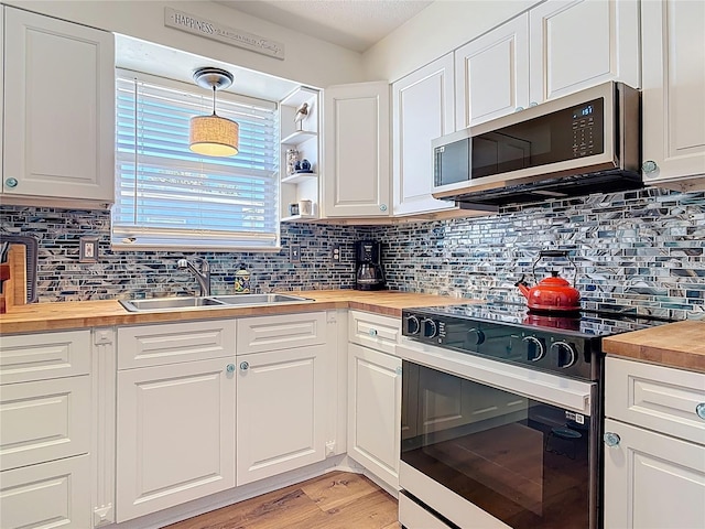kitchen with tasteful backsplash, range with electric stovetop, a sink, butcher block counters, and stainless steel microwave
