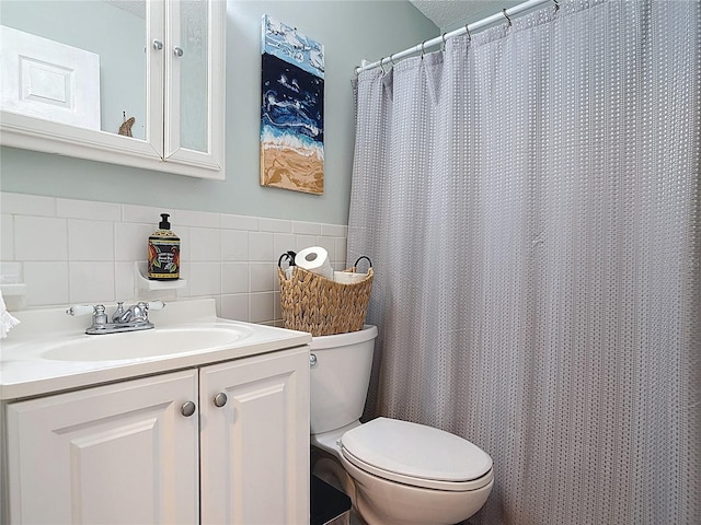 full bathroom with toilet, tile walls, vanity, and wainscoting