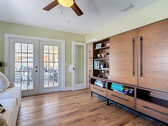interior space featuring french doors, a textured ceiling, visible vents, ceiling fan, and wood finished floors