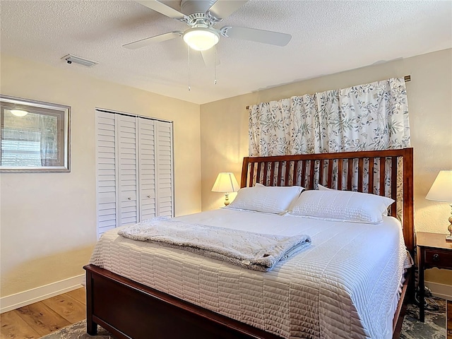 bedroom featuring a textured ceiling, a closet, visible vents, wood finished floors, and baseboards