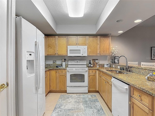 kitchen with light stone countertops, a sink, white appliances, and light tile patterned floors