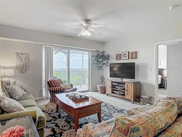 living area with a ceiling fan, baseboards, and light colored carpet