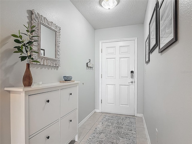 entryway with baseboards, a textured ceiling, and light tile patterned floors