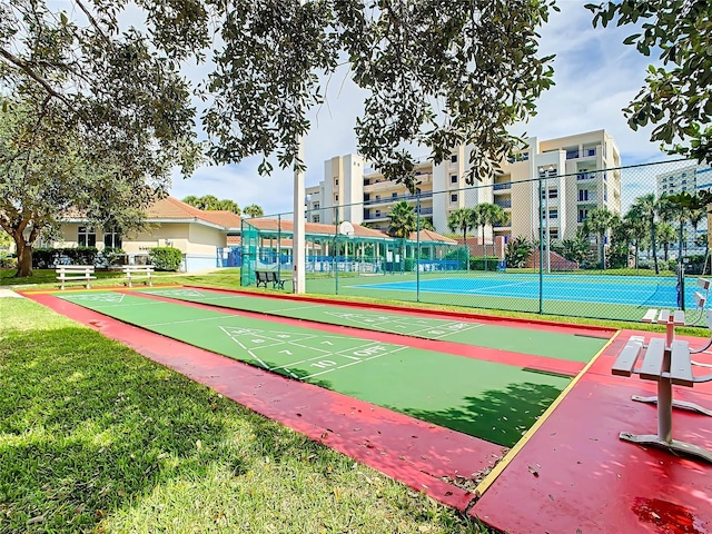 surrounding community featuring shuffleboard, a lawn, a tennis court, and fence