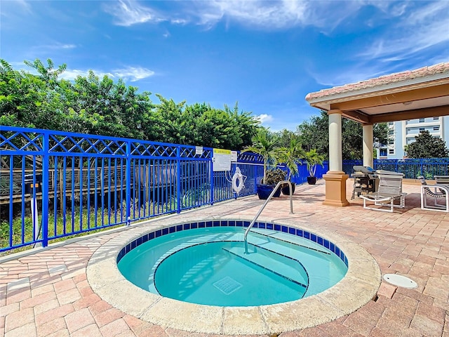 view of pool with a patio area, a community hot tub, and a fenced backyard