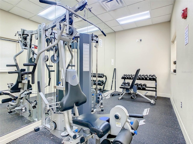 exercise room featuring baseboards, visible vents, and a paneled ceiling