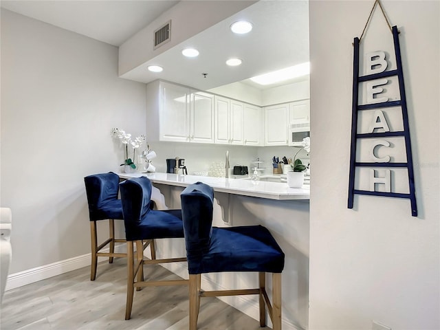5300 S Atlantic Ave Unit 10-205, New Smyrna Beach, FL 32169 - bar with light wood-style flooring, visible vents, baseboards, recessed lighting, and white microwave