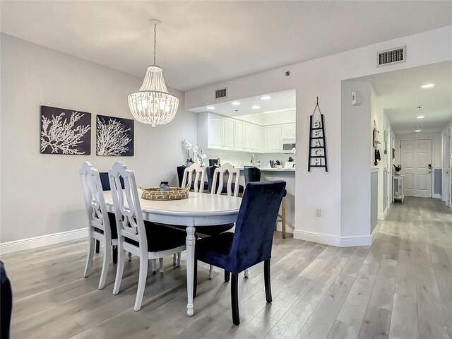5300 S Atlantic Ave Unit 10-205, New Smyrna Beach, FL 32169 - dining room with a notable chandelier, visible vents, and light wood-style flooring