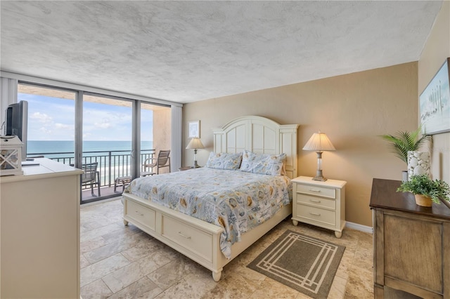 4139 S Atlantic Ave Unit A504, New Smyrna Beach, FL 32169 - bedroom with expansive windows, a water view, baseboards, access to outside, and stone finish floor