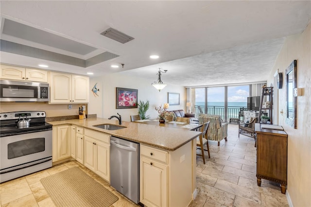 4139 S Atlantic Ave Unit A504, New Smyrna Beach, FL 32169 - kitchen with stainless steel appliances, visible vents, a sink, a peninsula, and cream cabinets