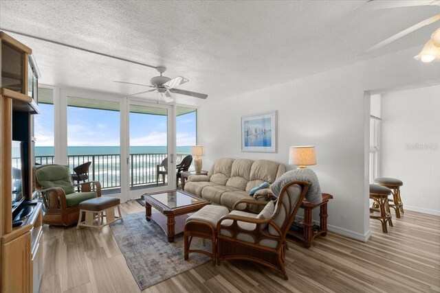 5201 S Atlantic Ave Unit 708A, New Smyrna Beach, FL 32169 - living area with ceiling fan, light wood-type flooring, a water view, a textured ceiling, and floor to ceiling windows