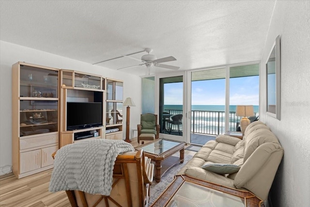 5201 S Atlantic Ave Unit 708A, New Smyrna Beach, FL 32169 - living room featuring a textured ceiling, ceiling fan, light wood finished floors, and expansive windows