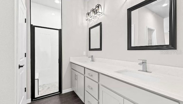 bathroom featuring double vanity, wood finished floors, baseboards, and a sink