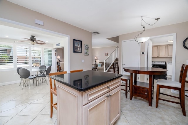 4150 S Atlantic Ave Unit 115D, New Smyrna Beach, FL 32169 - kitchen with light tile patterned flooring, dark countertops, visible vents, independent washer and dryer, and ceiling fan
