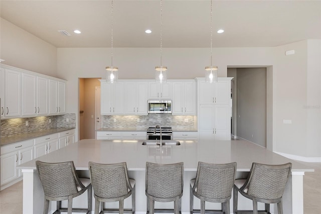 6277 W Fallsgrove Ln, Port Orange, FL 32128 - kitchen with an island with sink, stainless steel appliances, tasteful backsplash, and white cabinets