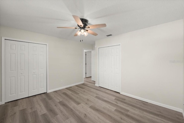 3644 Dame St, Port Orange, FL 32129 - unfurnished bedroom with baseboards, visible vents, wood finished floors, two closets, and ceiling fan