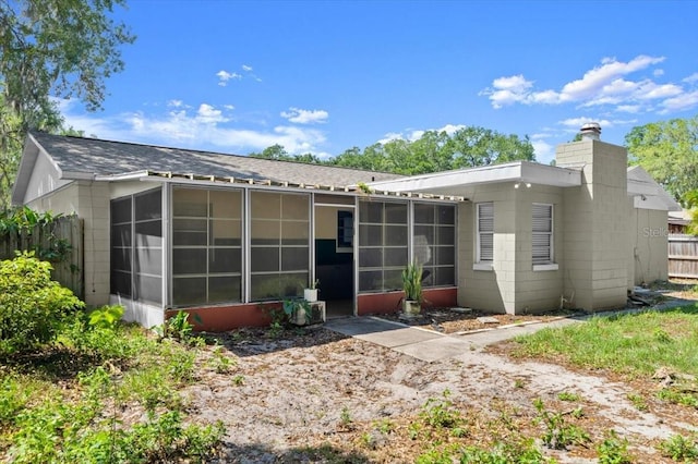 rear view of property featuring fence, a chimney, and a sunroom