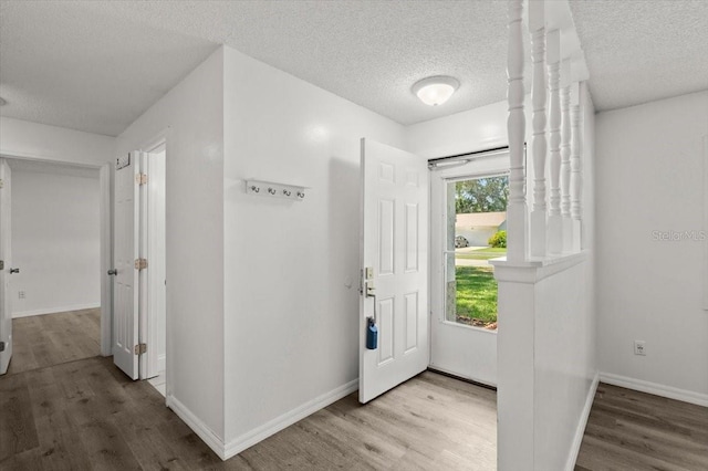 foyer featuring baseboards, wood finished floors, and a textured ceiling