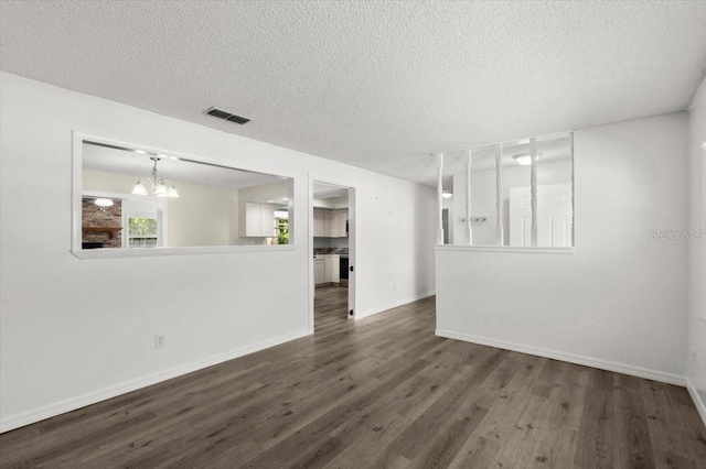 interior space with an inviting chandelier, wood finished floors, visible vents, baseboards, and a textured ceiling